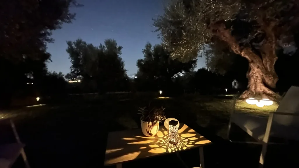 A lantern on the garden table after dark, with the lights of Kalamata below